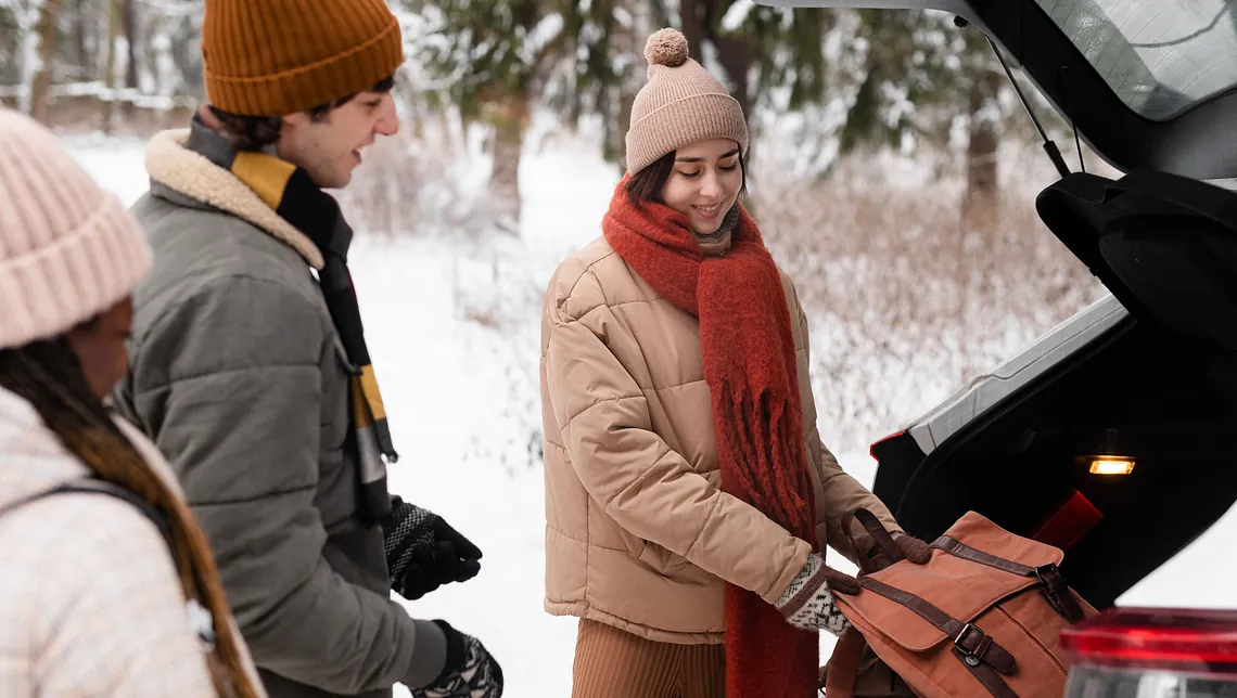 familj tar ut vinterkit ur bil en snöig dag